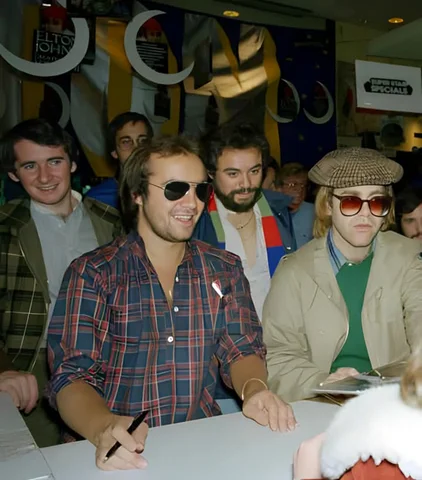Elton John, Bernie Taupin, John Reid, sign autographs at Sam Goody record store, New York, 1977.
