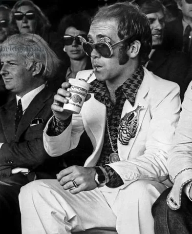English singer Elton John at a tennis match in Wimbledon (London) on june 26, 1974 (b/w photo)