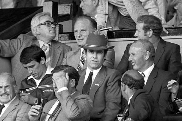 Rock and Roll legend Elton John (centre with hat) sits next to Watford Manager Graham Taylor (l) and General Manager Bertie Mee (r)