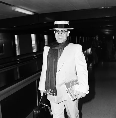 Elton John leaving Heathrow Airport for Barbados on his way to make a new record on the Island of Montserrat. 21st December 1983