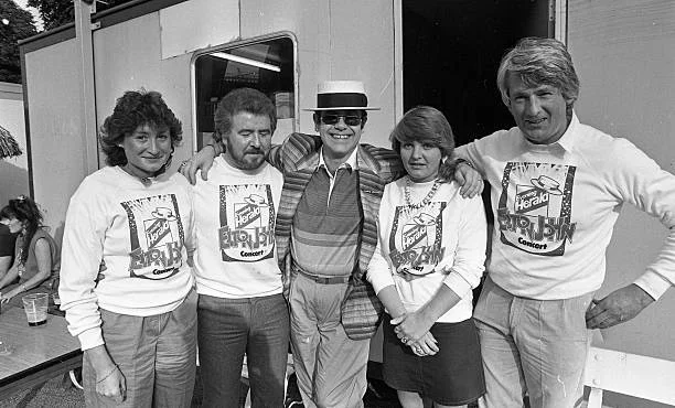 Backstage portrait of British musician Elton John (center) as he poses with unidentified others at the RDS, Dublin, Ireland, June 16, 1984.