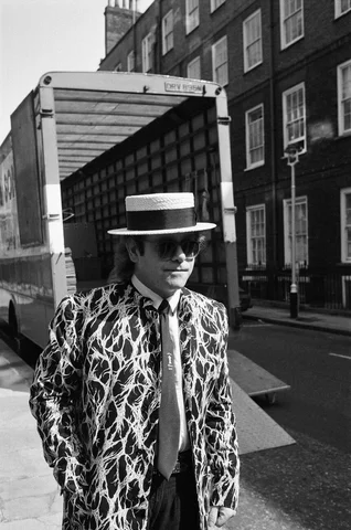 Elton John arriving at court. Elton is asking for a bigger share of the ¿20 million his early records made. He said he was "very green behind the ears when he signed away a fortune in royalties on his early In hits". 17th June 1985.