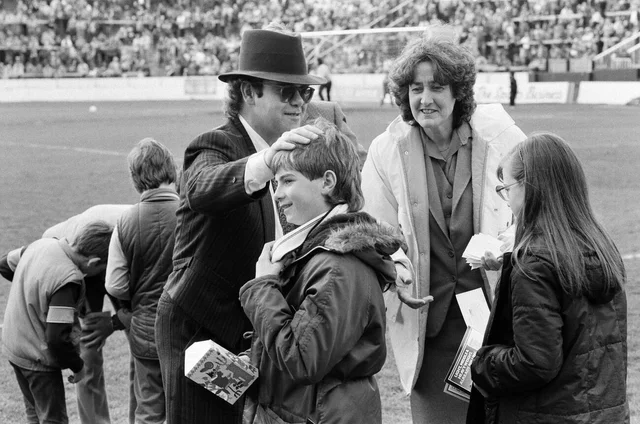 Pop star and Watford FC Chairman, Elton John, handing out Easter eggs to fans. Watford v Southampton football match. 6th April 1985.