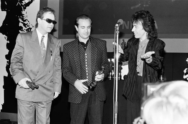 The Ivor Novello Awards at Gorsvenor House, London. Pictured, on stage Elton John, Bernie Taupin and Bill Wyman. 7th May 1986.