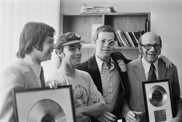 From left to right, music publisher Stephen James, songwriter Bernie Taupin, singer and pianist Elton John and Stephen's father, music publisher Dick James (1920 - 1986), UK, October 1972