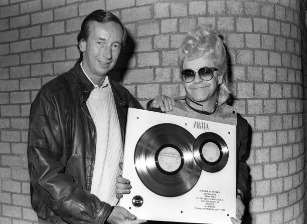 Elton John, with Jan Corduwener (Directer/President Phonogram Holland), with Award for sales of 'Nikita' in Holland, at Ahoy, Rotterdam, Netherlands 23rd April 1986.