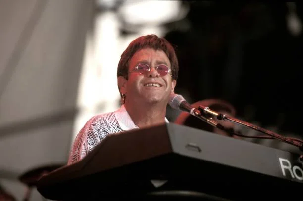 Elton John is shown performing on stage during a "live" concert appearance on July 28, 1989