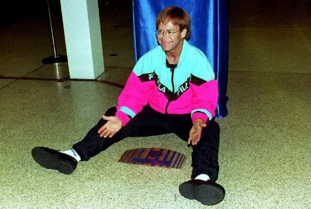 Elton John straddles a Walk of Fame plaque 09 October, 1992 at Madison Square Garden in New York. John becomes the first entertainer inducted to the Walk of Fame, joining 25 legendary athletes.
