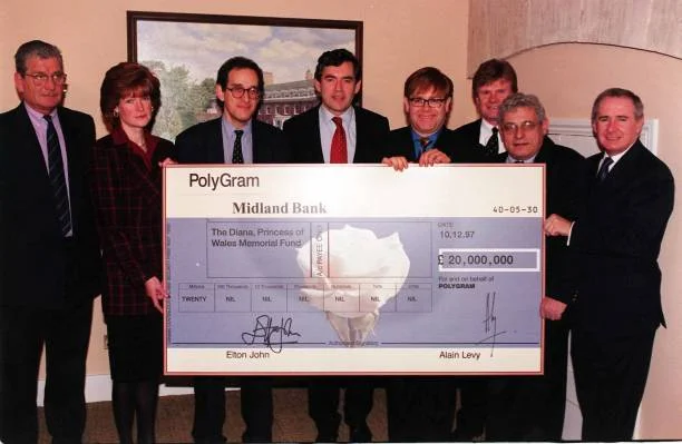 Elton John presents a cheque for 20 million - the first instalment of proceeds from the sale of his number-one hit, 'Candle in the Wind '97' - to the trustees of The Diana, Princess of Wales Memorial Fund at Kensington Palace in London